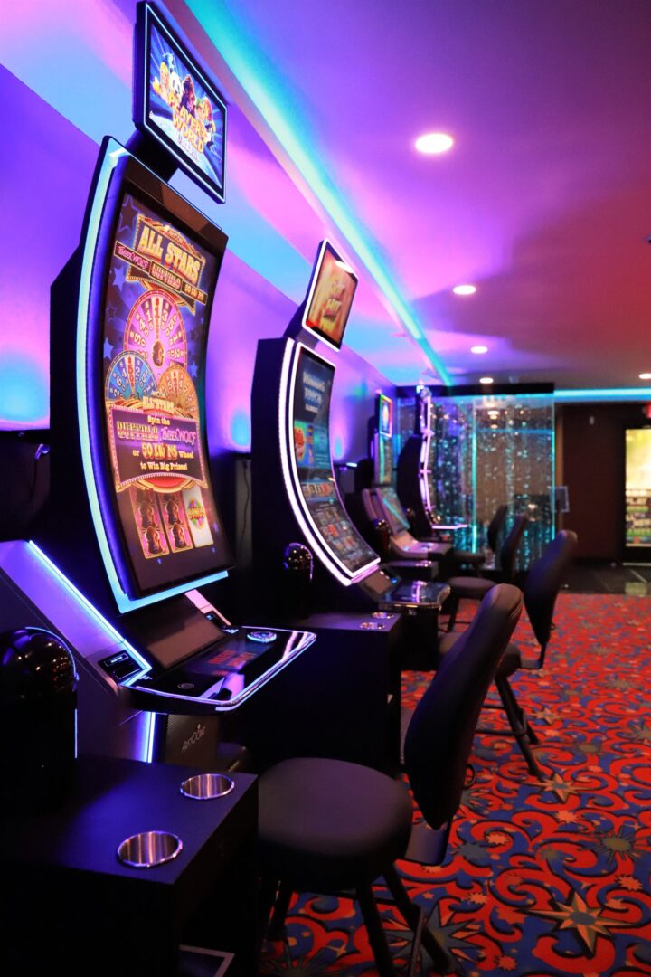 A row of slot machines in a room with purple lighting.
