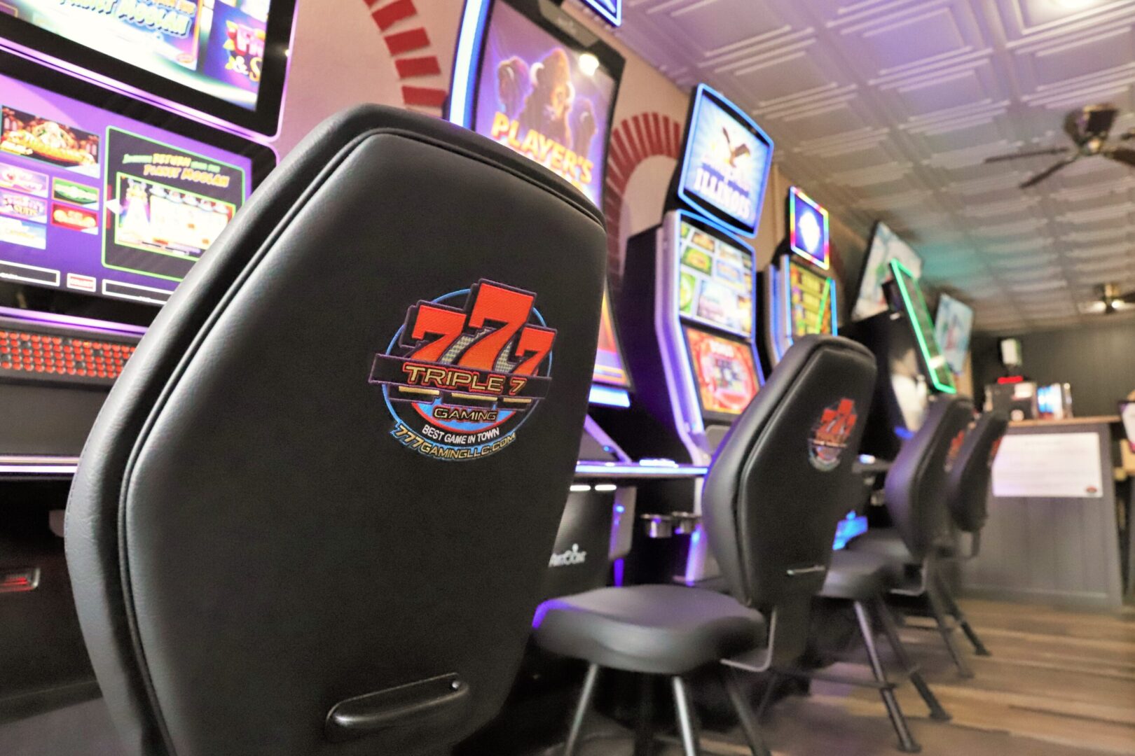 A row of black chairs in front of a wall with slot machines.