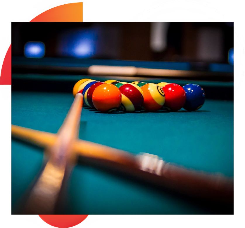 A pool table with three balls and two wooden sticks.